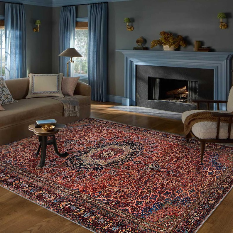 K&ouml;nnte beinhalten: Ein gro&szlig;er, rechteckiger persischer Teppich mit einem detaillierten Blumenmuster in Rot-, Blau- und Cremet&ouml;nen. Der Teppich befindet sich in einem Wohnzimmer, mit Sofa, Stuhl und Kamin im Hintergrund.