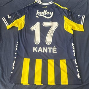Può includere: Maglia da calcio blu navy e gialla con il numero 17 e il nome Kante sul retro. La maglia presenta un logo Halley e una firma. Accenti gialli e strisce bianche adornano le maniche e i lati.