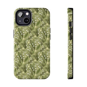 May include: A phone case featuring a repeating pattern of lily of the valley flowers and leaves on a light green background. The case has a black border and a camera cutout. The design includes white flowers, green leaves, and small yellow star accents.