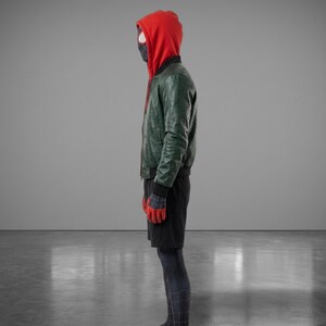 以下が含まれることがあります： 赤いフード付きスウェットシャツ、緑色のレザージャケット、黒いショートパンツ、赤と青の模様の手袋が特徴のコスチューム。コスチュームには黒いマスクと、クモの巣のデザインの全身スーツが含まれています。