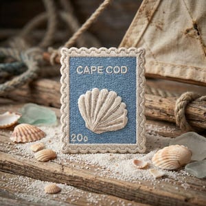 May include: A rectangular embroidered patch shaped like a postage stamp with a scalloped border. The patch features a blue background with the text CAPE COD and 20c in white, and a central white seashell illustration with detailed ridges.