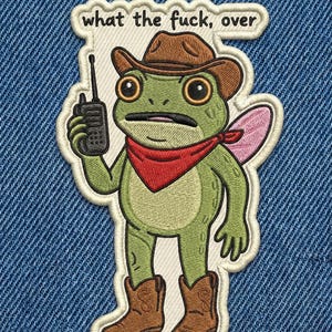 May include: Embroidered patch featuring a green frog wearing a cowboy hat, red bandana, and cowboy boots, holding a walkie-talkie. The patch has the text "what the fuck, over" in white letters.