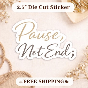 Può includere: Un adesivo fustellato con le parole "Pause, Not End;" in un carattere corsivo. Il testo è in tonalità marroni e grigie, con un bordo bianco. L'adesivo misura 6,35 cm.