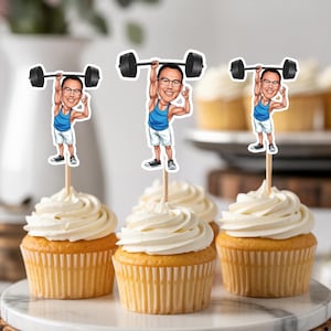 May include: Cupcakes with white frosting, each topped with a cartoon figure of a weightlifter. The weightlifter is wearing a blue tank top, white shorts, and black shoes, holding a barbell. The cupcakes sit on a marble surface.