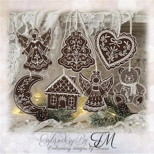 Könnte beinhalten: Eine Sammlung von sechs braunen Hängedekorationen mit weißen Stickereidetails, darunter ein Engel, ein Weihnachtsbaum, ein Herz, eine Mondsichel, ein Haus und ein Teddybär. Jedes Ornament weist aufwendige weiße Stickereien auf braunem Stoff auf.