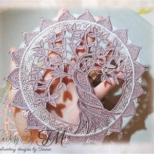 以下が含まれることがあります： 生命の樹のモチーフが施された、詳細な円形レースのデザイン。複雑な刺繍は、モーブと白の色合いで、スカラップエッジが付いています。繊細な職人技を示すように、デザインは手で持たれています。