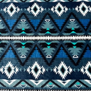 May include: A plush blanket with a geometric pattern in shades of blue, teal, black, and white. The design features diamond and triangle shapes arranged in horizontal rows. The blanket has a soft, textured appearance, suggesting a cozy and comfortable feel.