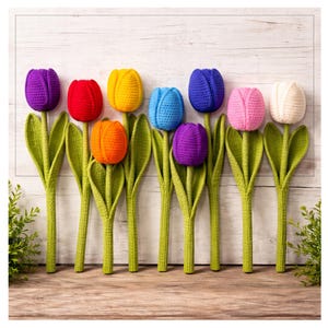 Op de afbeelding: Een verzameling handgemaakte gehaakte tulpen in verschillende kleuren, waaronder paars, rood, geel, blauw, oranje, roze en wit. Elke tulp heeft groene stelen en bladeren, geplaatst tegen een lichte houten achtergrond.