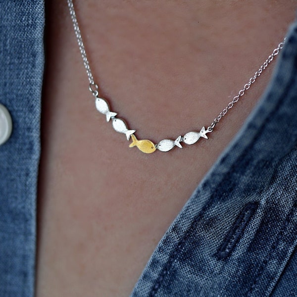 Against the current. Dainty silver necklace. Against the tide with one golden fish swimming upstream. School of fish necklace for her.