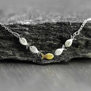 Swimming against the current. Dainty silver necklace. School of fish with one golden enameled fish swimming upstream. Gift for her. immagine 2