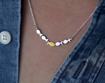 Against the current. Dainty silver necklace. Against the tide with one golden fish swimming upstream. School of fish necklace for her.