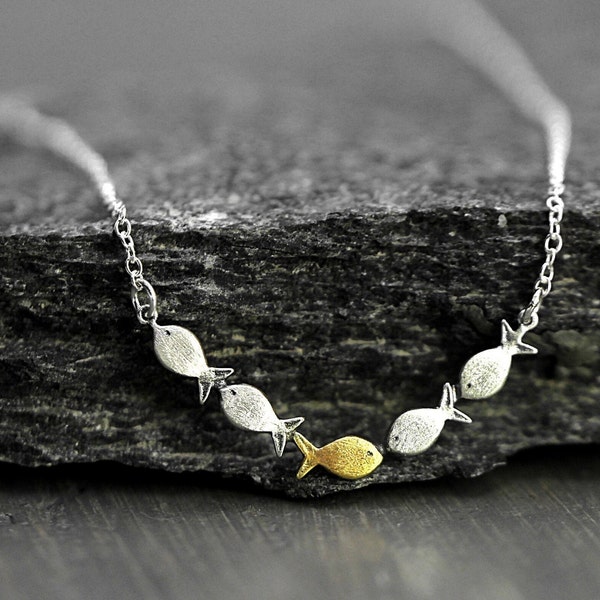 Swimming against the current. Dainty silver necklace. School of fish with one golden enameled fish swimming upstream. Gift for her.