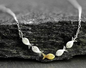 Swimming against the current. Dainty silver necklace. School of fish with one golden enameled fish swimming upstream. Gift for her.