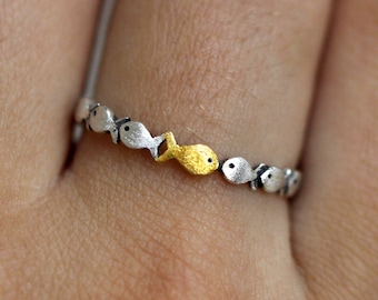 Gegen den Strom. Zarter schmaler Sterling Silber Ring. Fischschwarm mit einem goldenen, der stromaufwärts schwimmt. Geschenk für sie