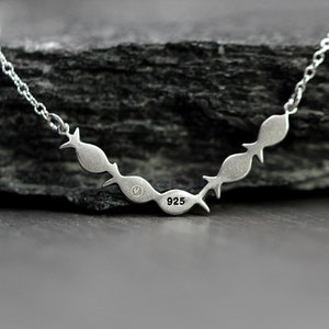 May include: Silver necklace with a chain and a pendant of five fish in a row. The pendant is stamped with "925" on the back.