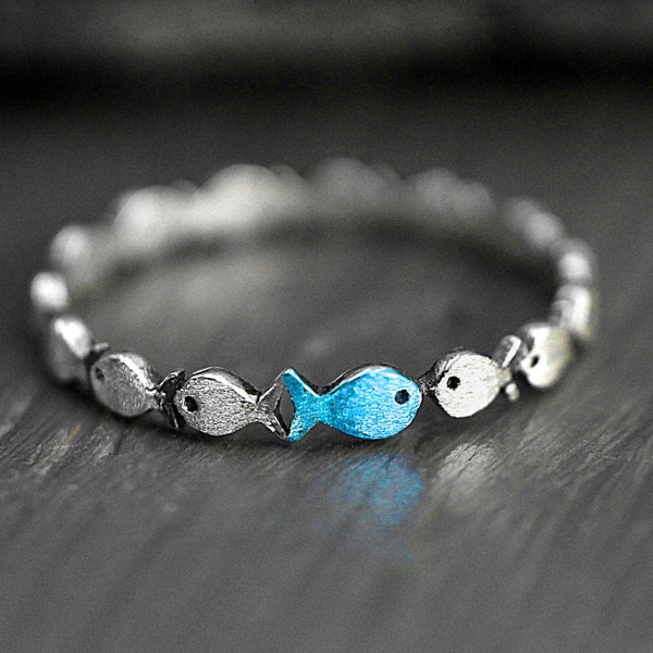 Gegen den Strom. Zarter schmaler Sterling Silber Ring. Fischschwarm mit einem blau türkisen Fisch. Wasserfest.