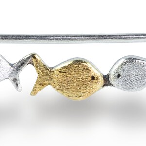 May include: A silver and gold fish charm bracelet with a textured finish. The bracelet features a series of small fish charms, each with a different design.