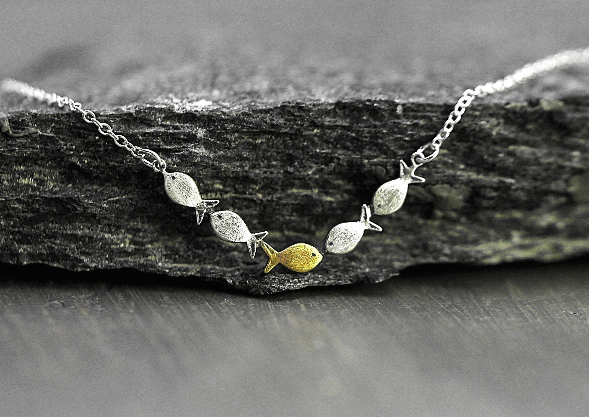 Swimming against the current. Dainty silver necklace. School of fish with one golden enameled fish swimming upstream. Gift for her.