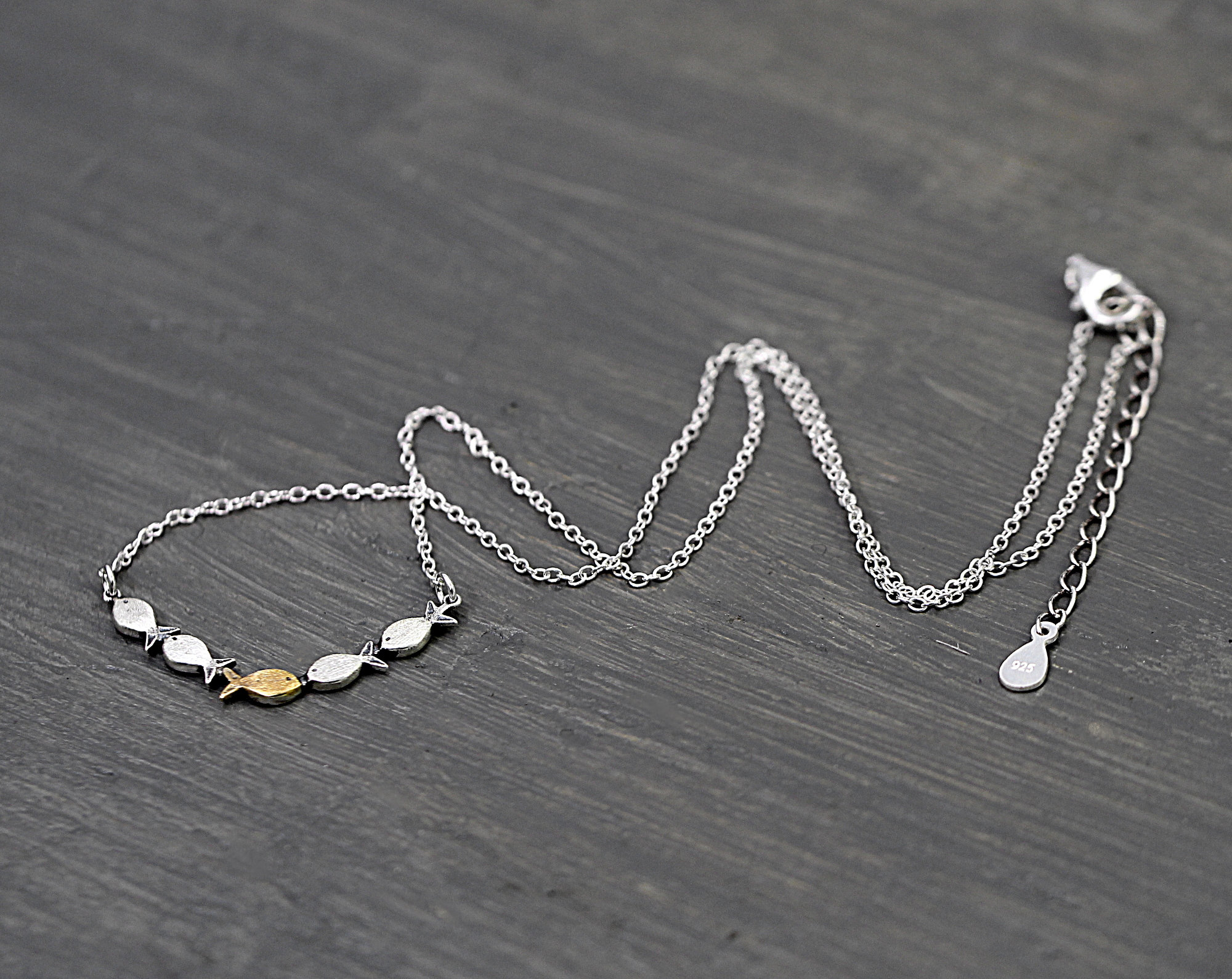Swimming against the current. Dainty silver necklace. School of fish with one golden enameled fish swimming upstream. Gift for her.