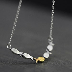 May include: A silver chain necklace with a pendant of five silver fish, one of which is gold.