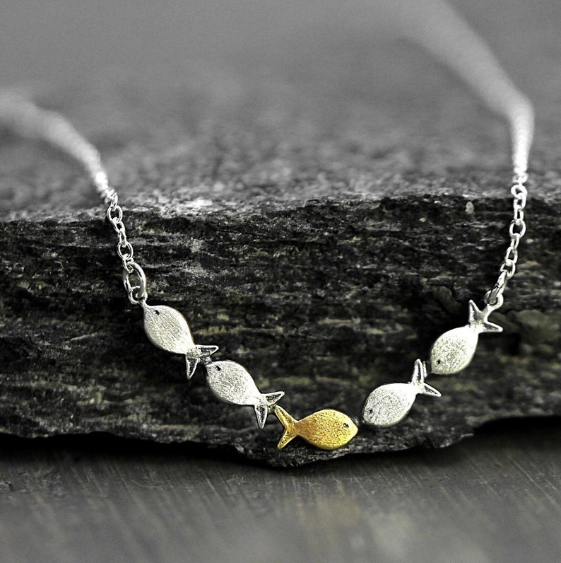 Swimming against the current. Dainty silver necklace. School of fish with one golden enameled fish swimming upstream. Gift for her. immagine 1
