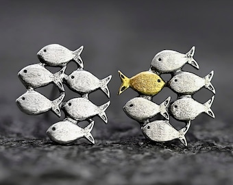 Swimming against the current. Mismatch stud earrings. School of fish with golden fish swimming upstream