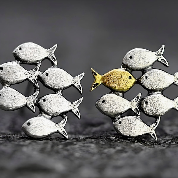 Swimming against the current. Mismatch stud earrings. School of fish with golden fish swimming upstream