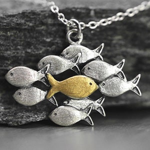 Tegen de stroom in zwemmende zilveren ketting. School vissen met één gouden vis die stroomopwaarts zwemt. Kettingen voor vrouwen. Cadeaus voor moeder.