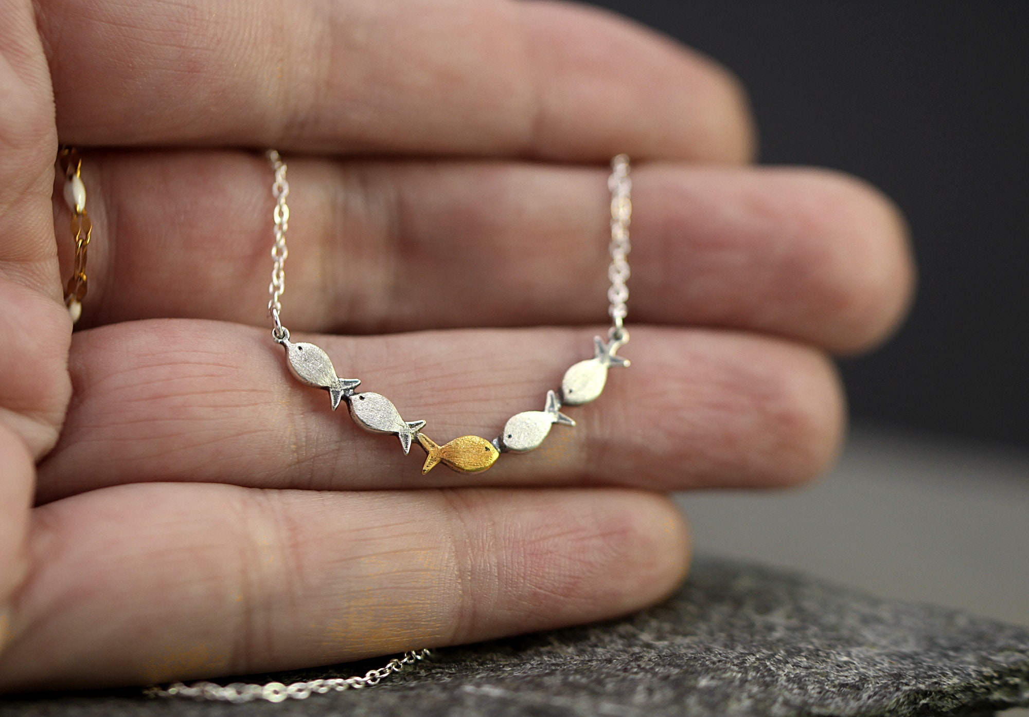 Swimming against the current. Dainty silver necklace. School of fish with one golden enameled fish swimming upstream. Gift for her.