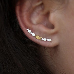 May include: A silver and gold fish ear crawler earring. The earring is made up of a line of small fish, alternating between silver and gold.