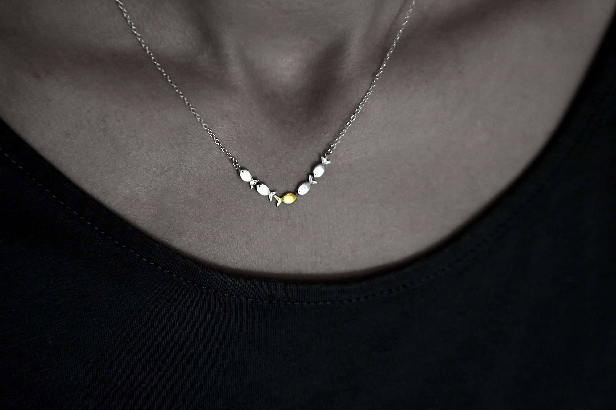 Swimming against the current. Dainty silver necklace. School of fish with one golden enameled fish swimming upstream. Gift for her.