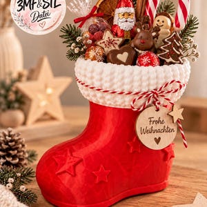 May include: A red Christmas stocking container with a white textured cuff, filled with assorted chocolates, a candy cane, and dried fruit. A wooden tag attached with red and white twine features the text Frohe Weihnachten and a heart symbol.