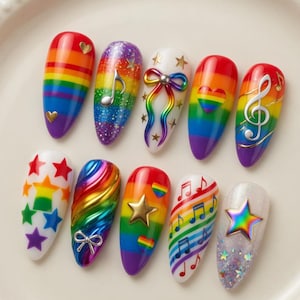 May include: A collection of ten artificial nails, each with a unique design. The nails feature rainbow colors, stars, musical notes, and bows. The nails are arranged on a white plate with a decorative edge, showcasing a variety of nail art.