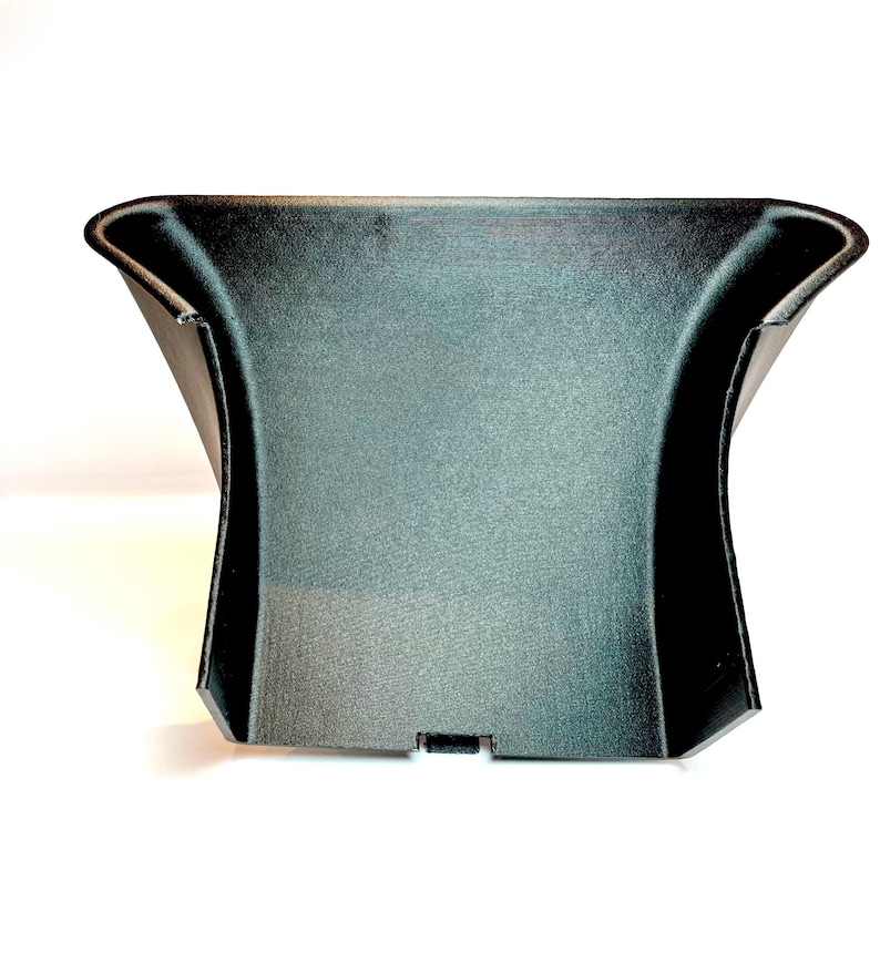 以下が含まれることがあります： 黒いプラスチック製の自動車部品で、表面はテクスチャ加工されています。 上部は湾曲し、側面はフレア状になっており、下部に小さな長方形の切り欠きがあります。 車両のインテリアに組み込むように設計されています。