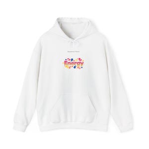 May include: White hoodie with a front pocket and drawstring hood. The hoodie features the text "Dopamine Decor" above a colorful "Energy" graphic in yellow, pink, blue, and green.