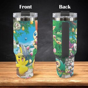 May include: A stainless steel tumbler featuring a colorful cartoon design with various characters set against a landscape of trees, a blue sky, and a stone path. The front and back of the tumbler are shown.