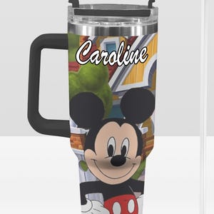 May include: A stainless steel tumbler featuring Mickey Mouse with a black handle and lid. The tumbler has a cartoon background and the name "Caroline" in script. Includes a clear straw.