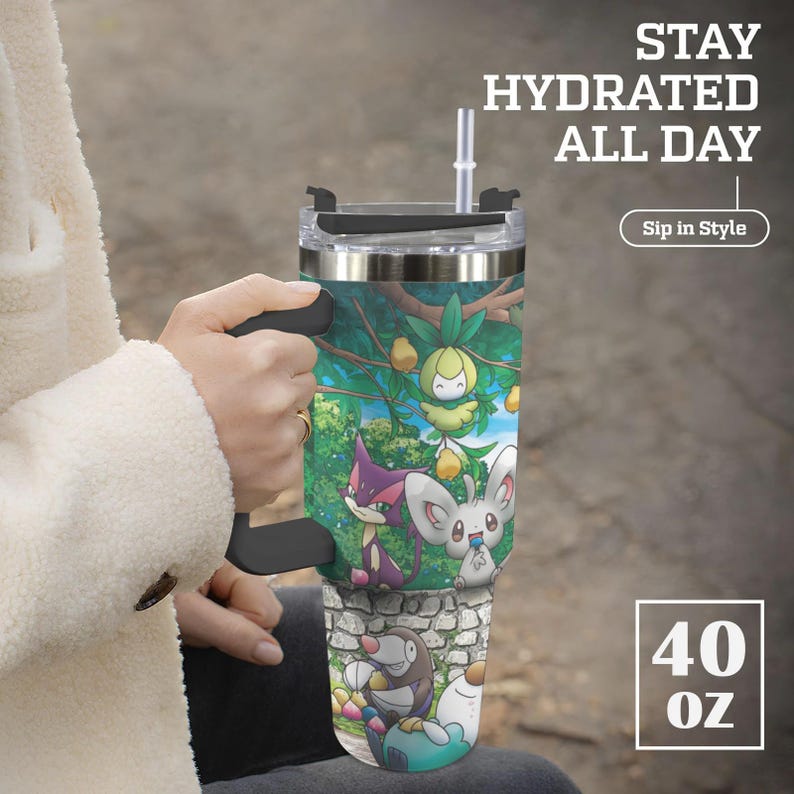 May include: A stainless steel tumbler with a black handle and straw, featuring a colorful cartoon design. The tumbler has the text "Stay Hydrated All Day" and "Sip in Style". It holds 40 oz.