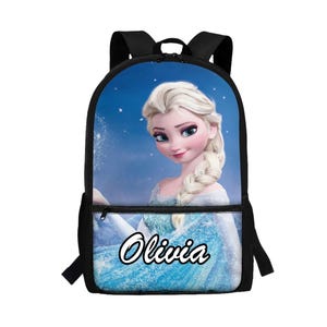 Puede incluir: Una mochila negra con un gr&aacute;fico impreso de un personaje rubio con una trenza lateral y un vestido azul claro sobre un fondo azul estrellado. El nombre Olivia est&aacute; impreso en letras blancas con un borde negro en el bolsillo delantero.