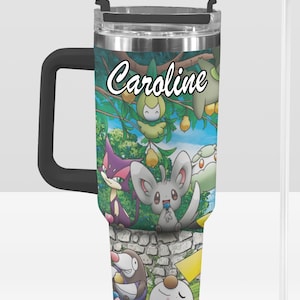 May include: A stainless steel tumbler with a black handle and lid, featuring a colorful cartoon design with the name "Caroline" in white script. The design includes various cartoon characters and a stone wall.