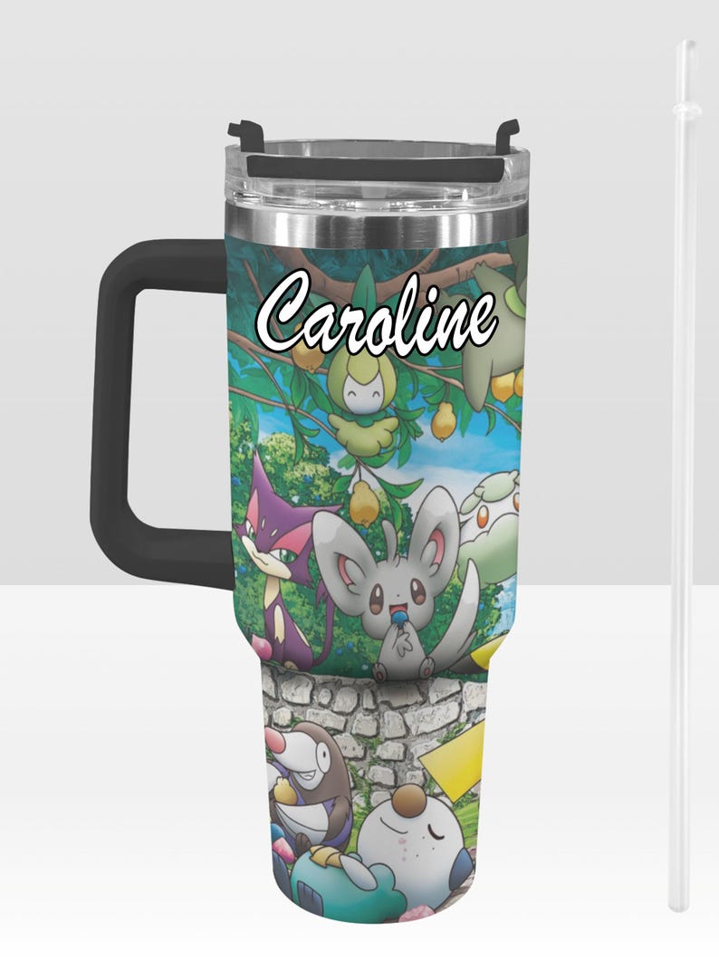 May include: A stainless steel tumbler with a black handle and lid, featuring a colorful cartoon design with the name "Caroline" in white script. The design includes various cartoon characters and a stone wall.