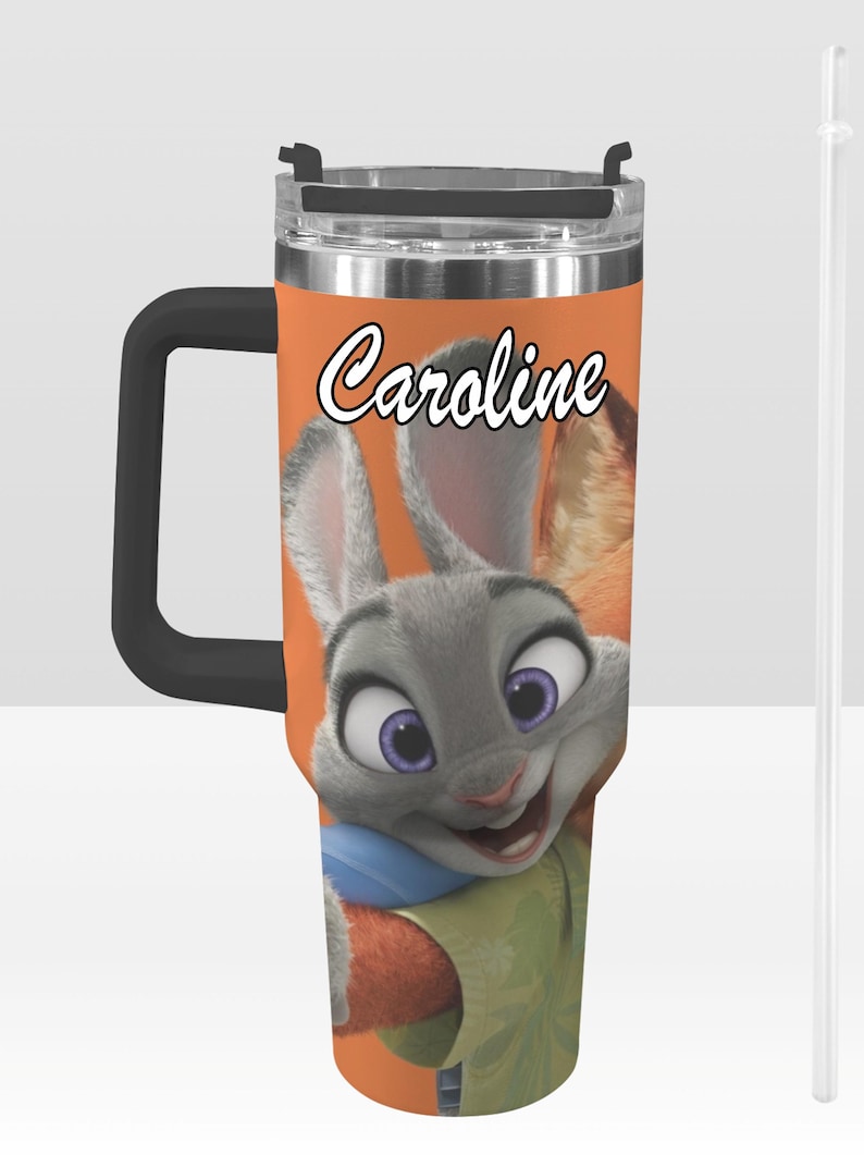 May include: A stainless steel travel mug with a black handle and lid. The mug features a cartoon image of Judy Hopps from Zootopia, with the name "Caroline" in white script. The background is orange, and a clear straw is included.