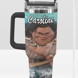 May include: A stainless steel tumbler with a black handle and a clear straw. The tumbler features a cartoon image of a character with tattoos and the name "Caroline" in white script. The background shows a blue ocean scene.