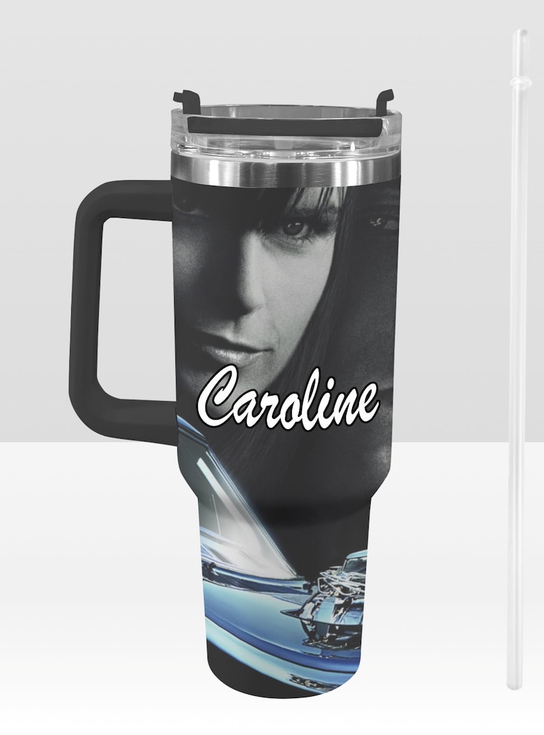 May include: Black and silver insulated tumbler with a black handle and a clear straw. The tumbler features a black and white image of a woman's face with the name "Caroline" in white script. A blue car is at the bottom.