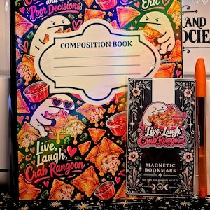May include: A composition book and a magnetic bookmark featuring cartoon characters eating crab rangoon. The book text reads Powered by Crab Rangoons and Poor Decisions and In My Crab Rangoon Era. The bookmark reads Live, Laugh, Crab Rangoon.