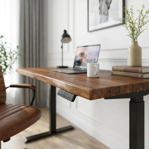 May include: A wooden desk with a dark brown finish and black legs. A laptop, white mug, and books sit on the desk. A black lamp and a brown leather chair are also visible. The desk has a control panel on the side.