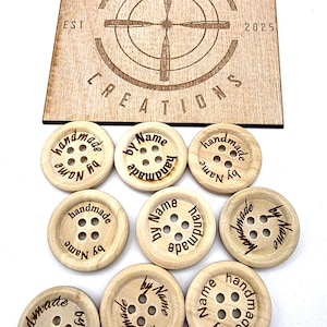 May include: Wooden buttons engraved with "handmade by Name" around the edges. A wooden sign in the background displays "BULLET CREATIONS EST 2025". The buttons have four holes. The buttons are approximately 2.5 cm in diameter.