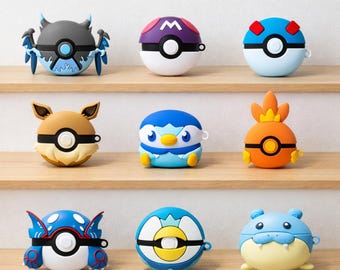 May include: Nine character-themed cases for electronic devices in various colours. The cases are designed to resemble creatures and characters, including blue, orange, yellow, and brown. The cases are displayed on wooden shelves, providing a decorative display.