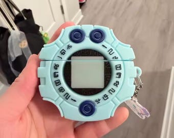 May include: A light blue Digivice-themed AirPod case. The case has a square screen in the centre, with blue buttons and symbols around the edges. A small keychain is attached to the side.