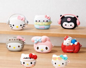 May include: A selection of brightly coloured AirPod cases featuring cartoon characters. Designs include a white Hello Kitty case with headphones, a stacked pastel case with the word "Cute", and a black case with a skull and headphones. Other cases feature various characters.